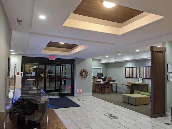 A hotel lobby with a reception desk, seating area, and a glass display case with a decorative item. - Holiday Inn Express & Suites Claypool Hill (Richlands Area) by IHG (Pounding Mill)