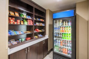 A self-service snack and drink vending area with various packaged snacks and a selection of bottled beverages. - Holiday Inn Express & Suites Ashland by IHG (Ashland)