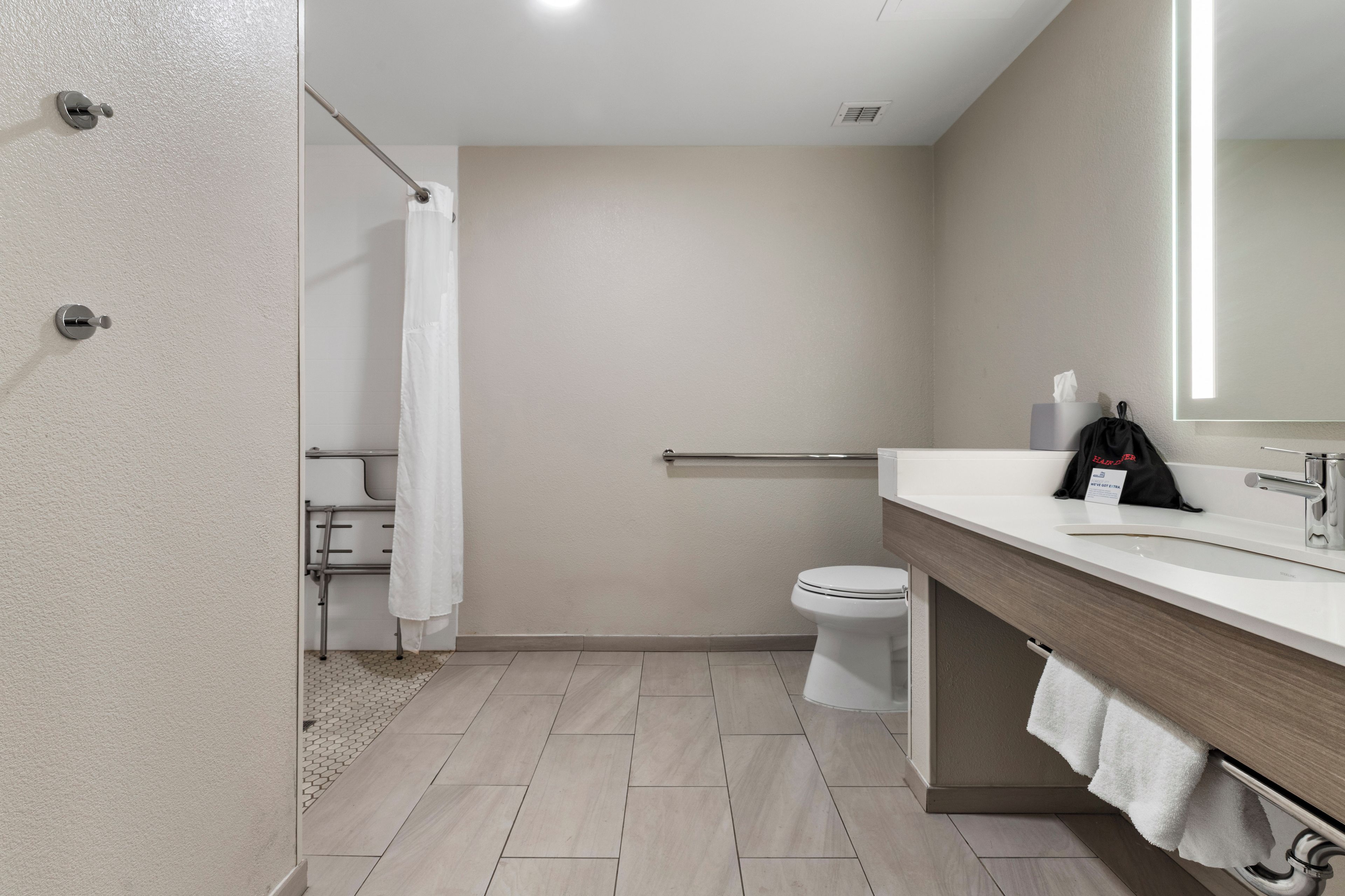 Un baño moderno con ducha, inodoro y tocador con perchero.