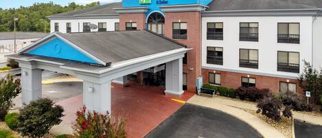 A Holiday Inn Express & Suites building with a covered entrance and a parking lot.