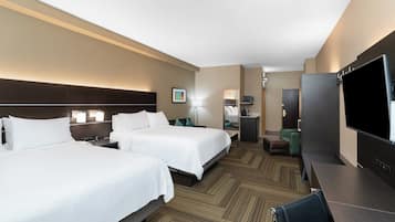 A hotel room with two beds, a desk, a television, and a mirror.