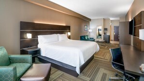 A hotel room with a large bed, a desk, a chair, and a sofa.