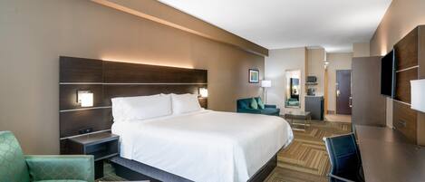 A hotel room with a large bed, a desk, a chair, and a sofa.