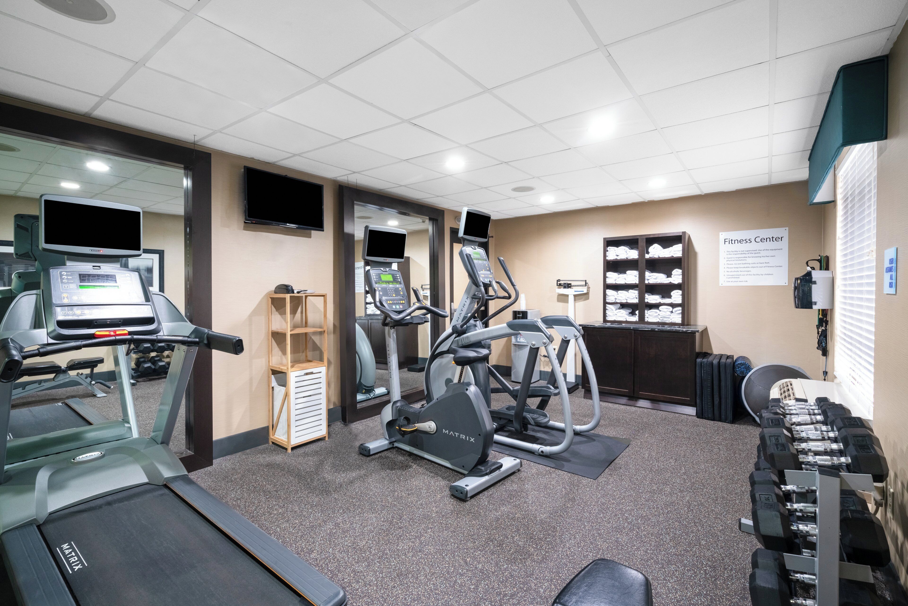 A fitness center with treadmills, an elliptical, and a weight bench.