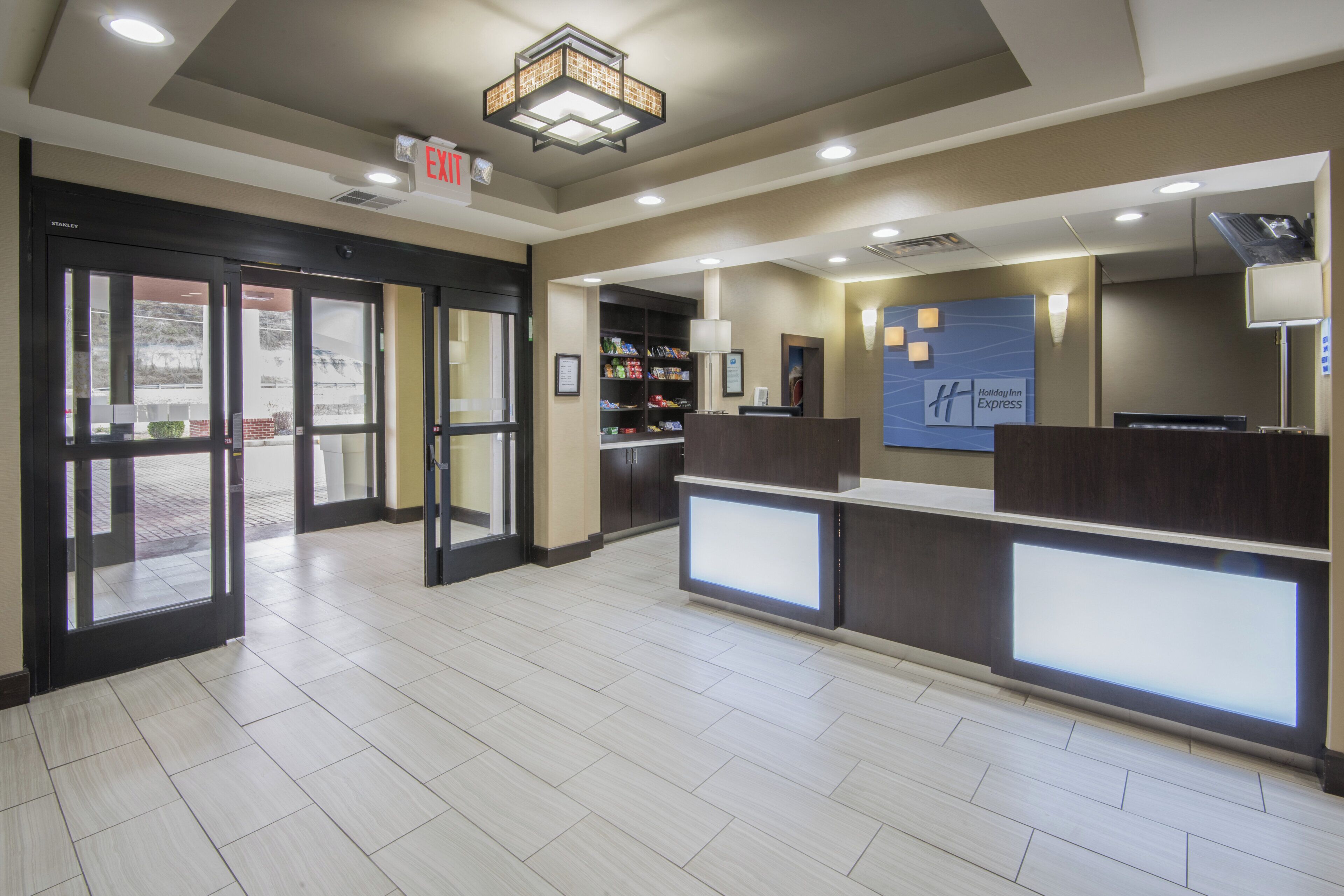 A hotel reception area with a glass door entrance, a reception desk, and a Holiday Inn Express sign.