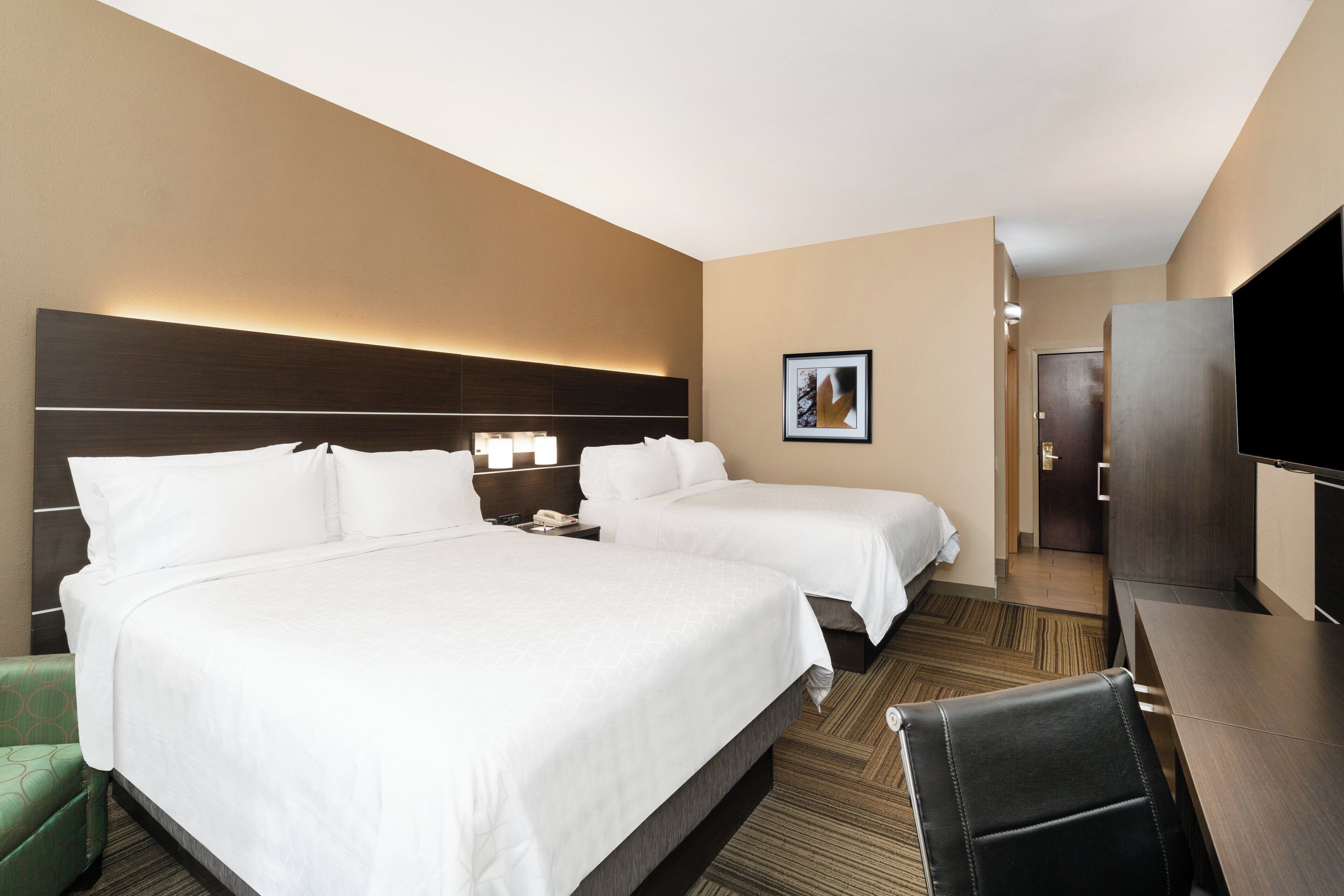 A hotel room with two beds, a desk, a chair, a television, and a picture on the wall.