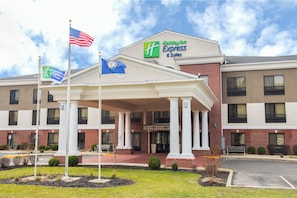 A Holiday Inn Express & Suites hotel with a covered entrance, flagpoles, and a brick facade.