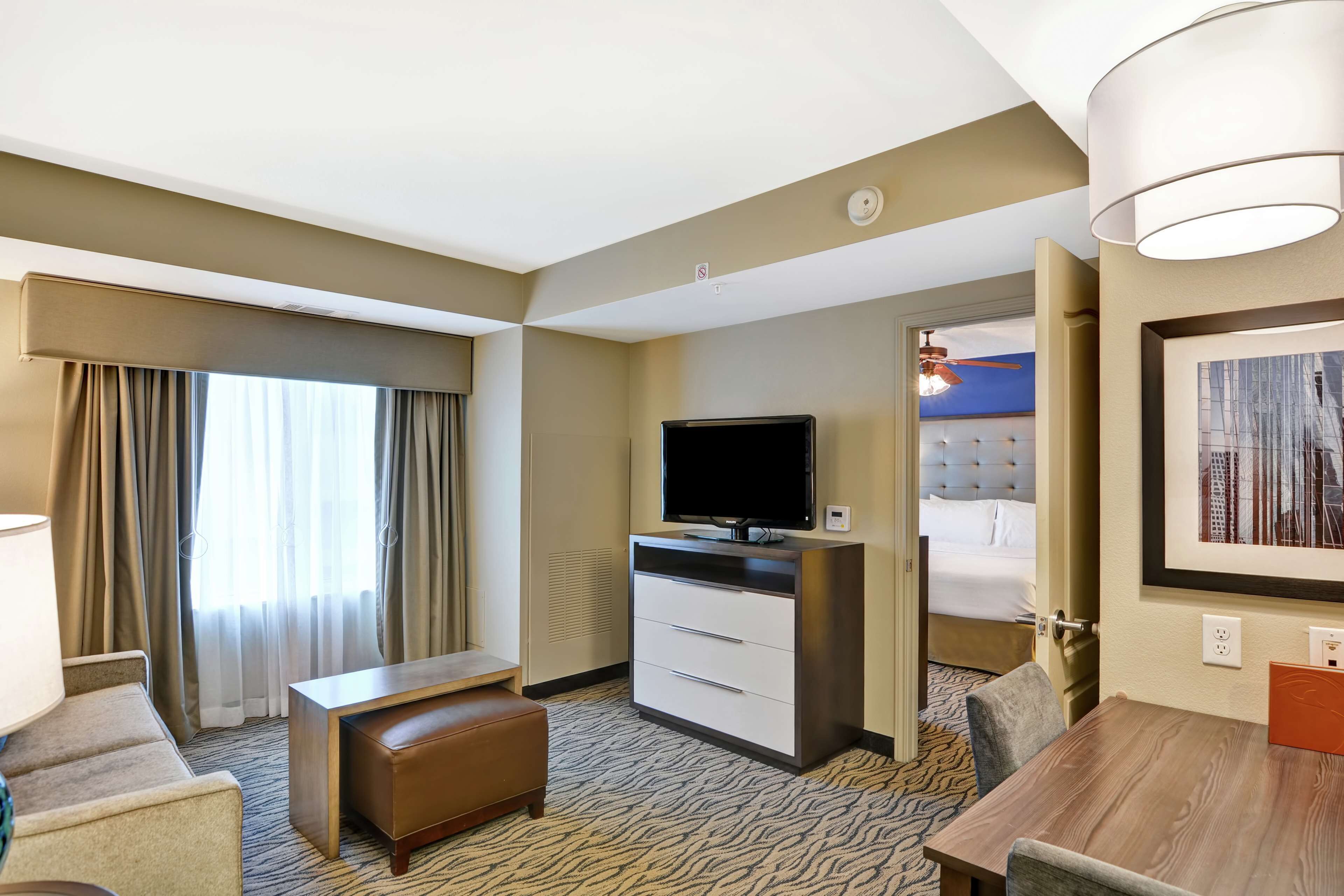 A hotel room with a bed, a television, a desk, and a dining table.