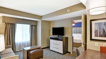A hotel room with a bed, a television, a desk, and a dining table.