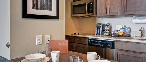 Une cuisine moderne équipée d’une table à manger pour quatre personnes, d’un four à micro-ondes, d’une machine à café et d’un lave-vaisselle.