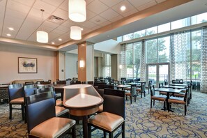 A spacious dining area with multiple tables and chairs, large windows, and a patterned carpet. - Homewood Suites by Hilton Houston Near the Galleria (Houston)