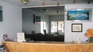 A reception desk with a wooden finish, a framed picture on the wall, and a small statue on the counter.