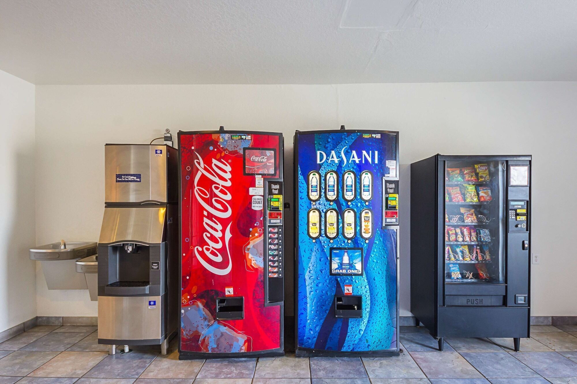 Three beverage vending machines, a water dispenser, and a trash bin.