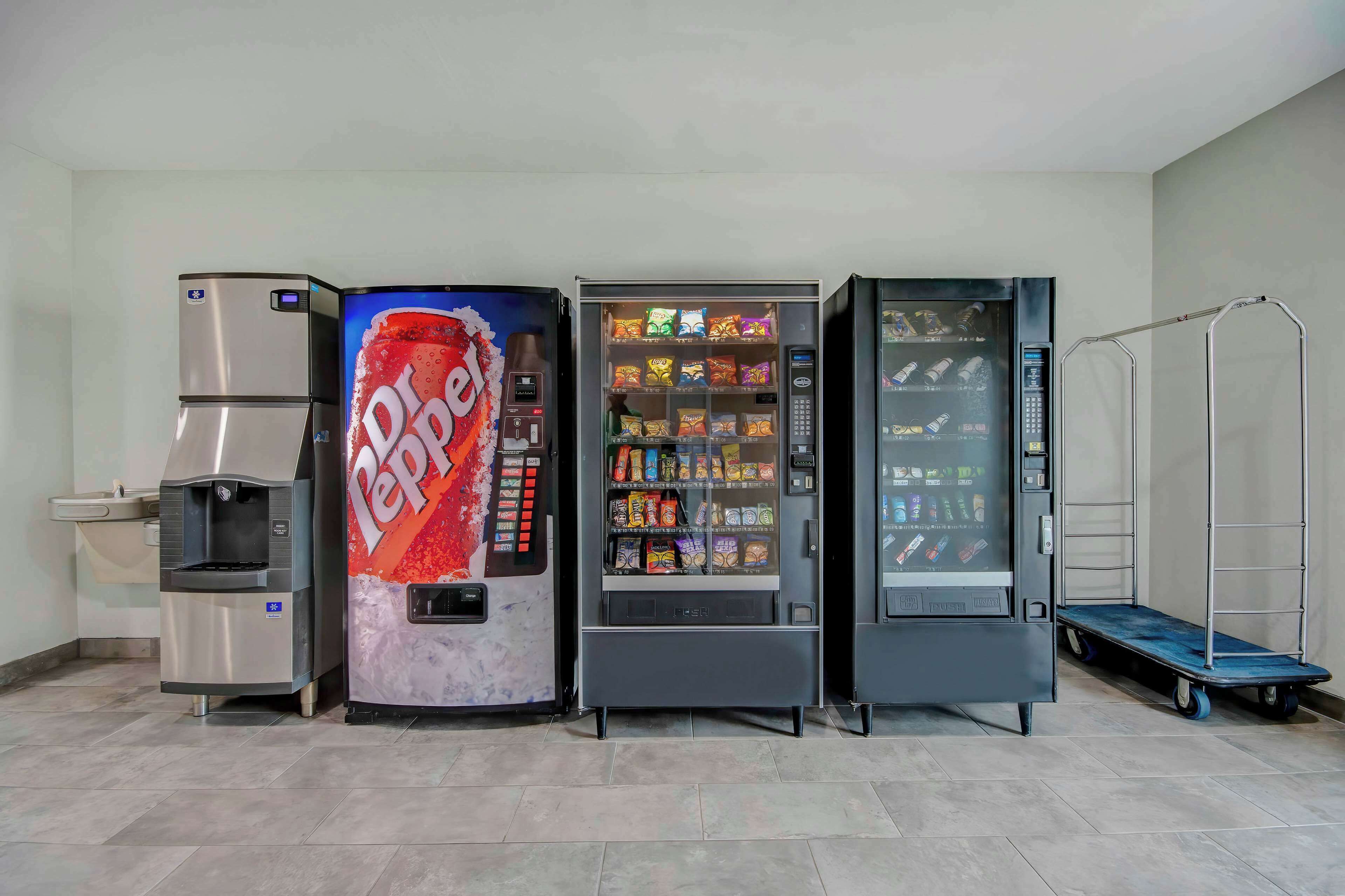 Zona de máquinas expendedoras con dispensador de Dr. Pepper, máquina expendedora de bocadillos y dispensador de bebidas.