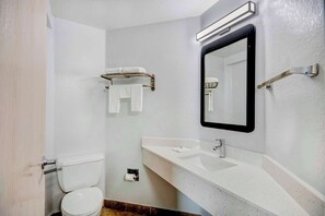 Un baño con un lavabo blanco, un espejo y un perchero para toallas.