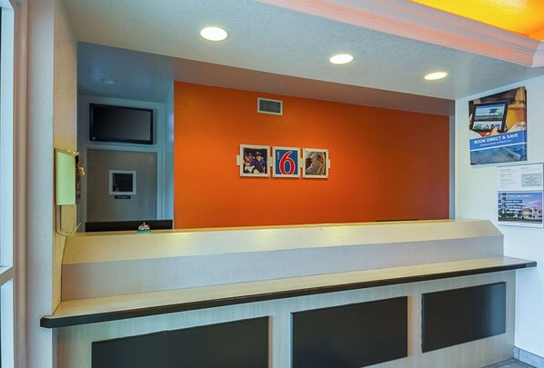 A reception area with a counter, a television, and a wall with three framed pictures.