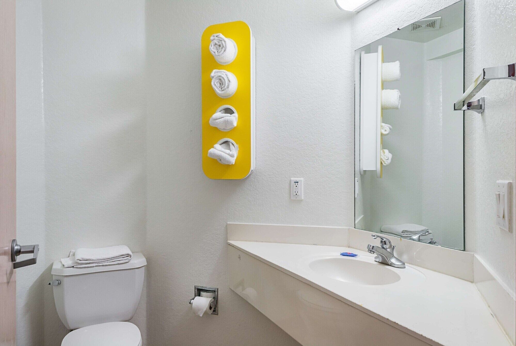 Een badkamer met toilet, wastafel en spiegel.