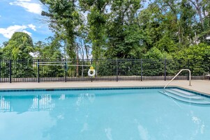 Una piscina al aire libre, sombrillas, sillones reclinables de piscina