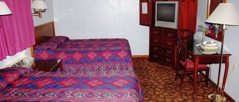 Una habitación de hotel con una cama grande, un escritorio con silla, un televisor y un espejo.