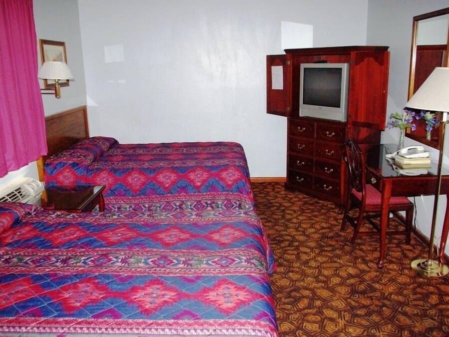 Een hotelkamer met een groot bed, een bureau met stoel, een televisie en een spiegel.