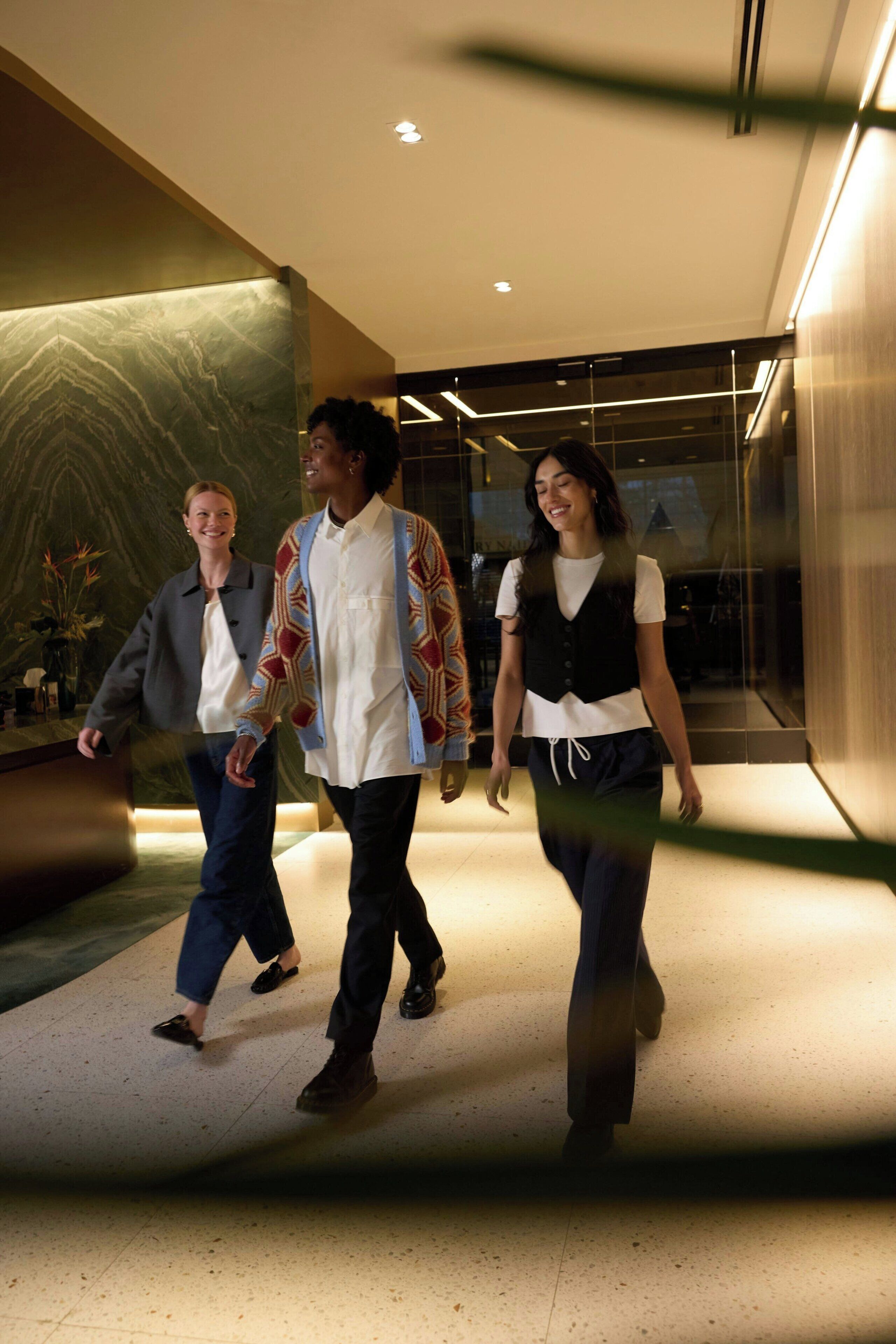 Een moderne hotellobby met marmeren wanden, een receptiebalie en een glazen scheidingswand.
