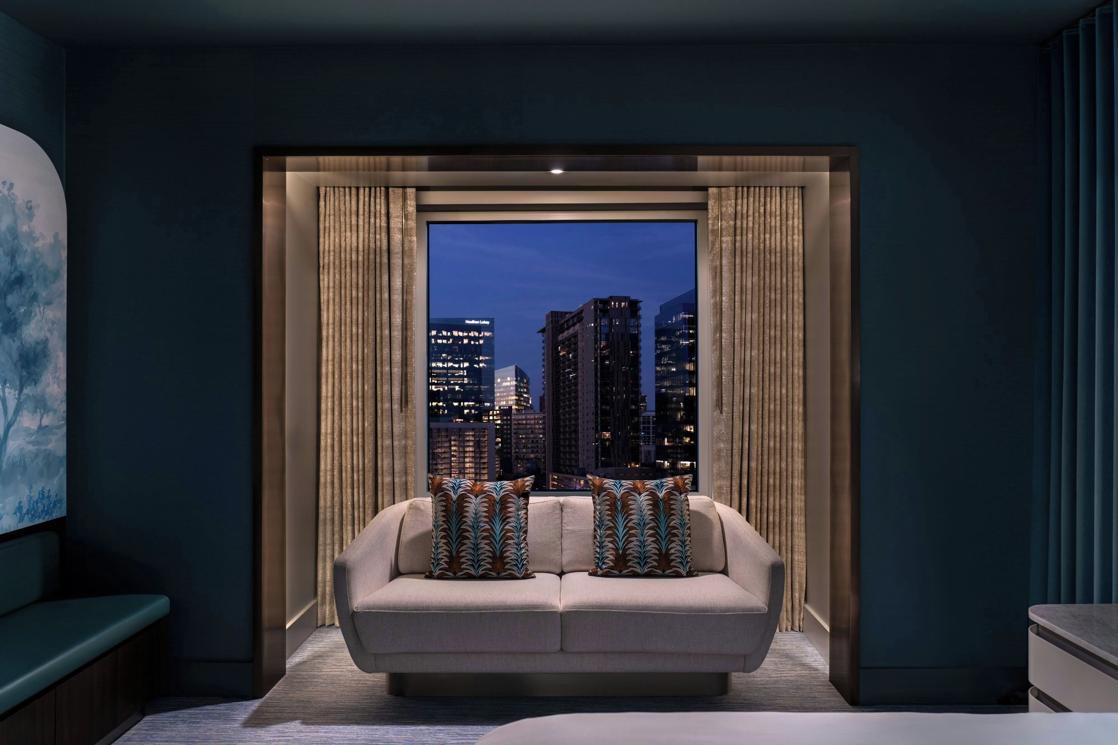 A modern living room with a city view, a sofa, and decorative pillows.