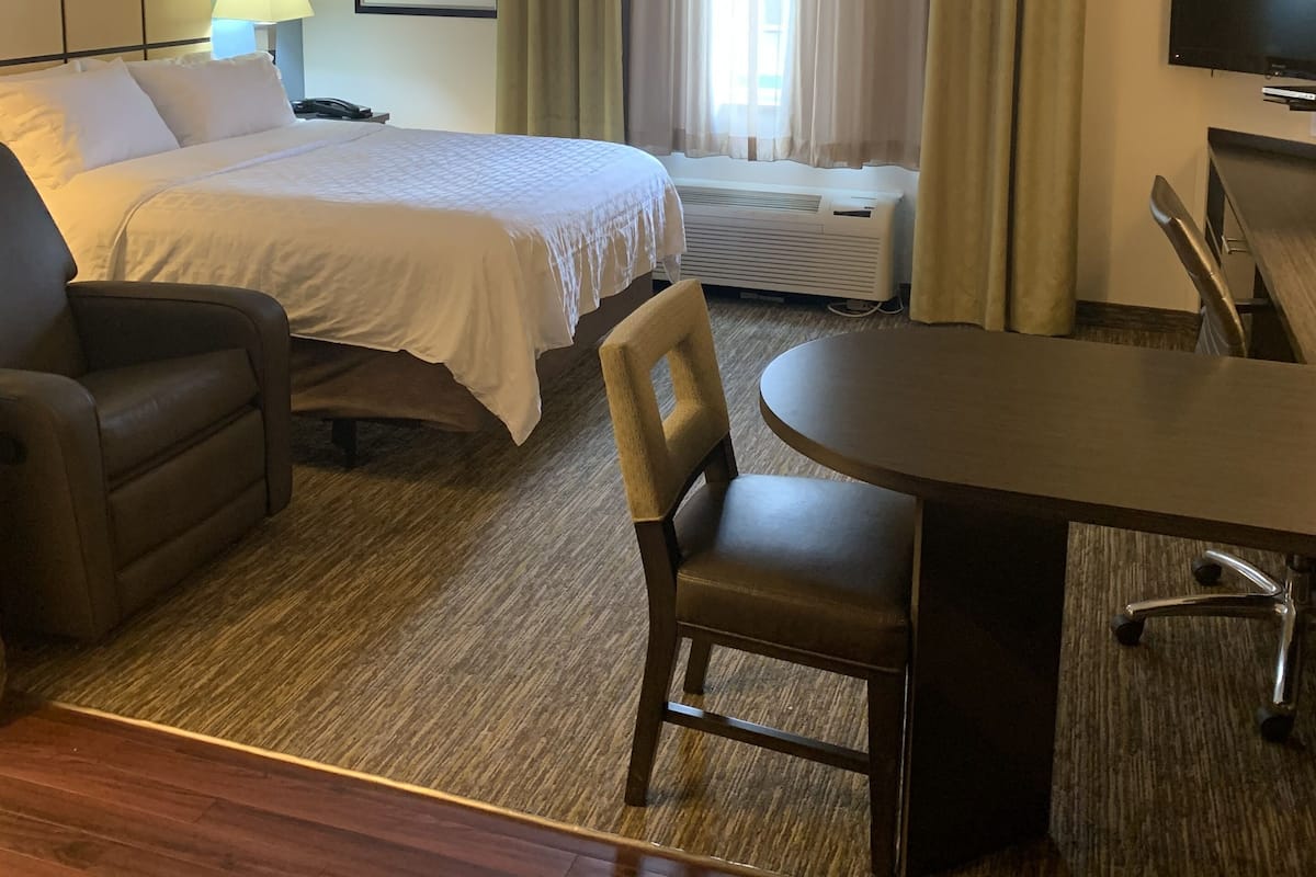 Een hotelkamer met een bed, een bureau, een stoel, een televisie en een raam met gordijnen.