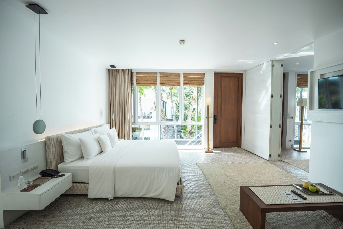 A modern hotel room with a large bed, a bedside table, a desk, and a TV.