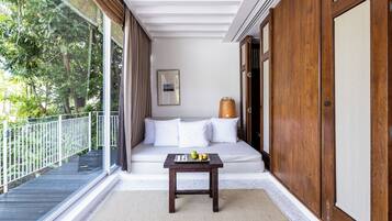 A balcony with a wooden table, white sofa, and a wicker basket.