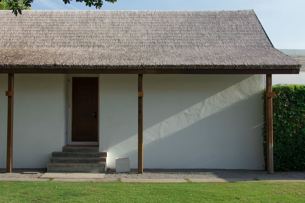 A building with a thatched roof, a wooden door, and a small set of steps leading to the entrance.