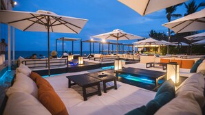 A poolside area with lounge chairs and umbrellas, overlooking the sea.
