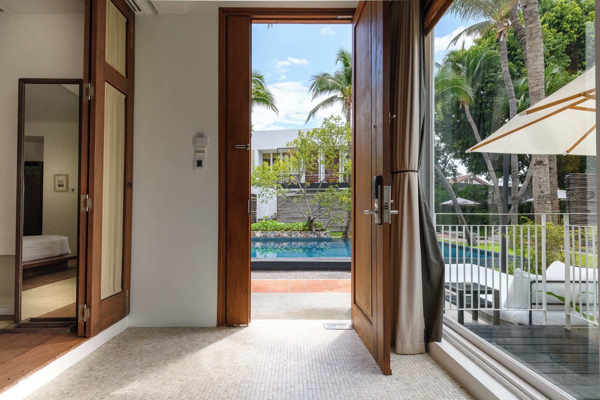 A hotel room with a view of a swimming pool and palm trees.