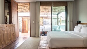 A modern bedroom with a large bed, wooden furniture, and a view of the outdoor area.