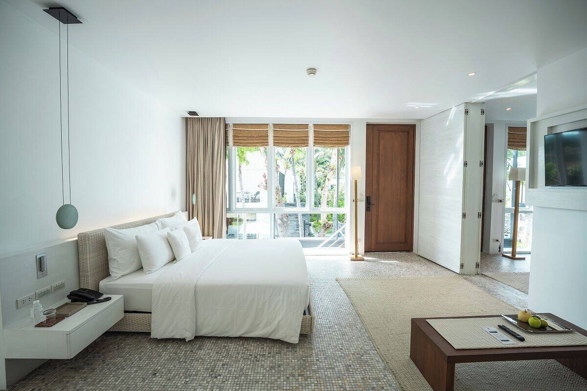 A modern hotel room with a large bed, a bedside table, a desk, and a TV.