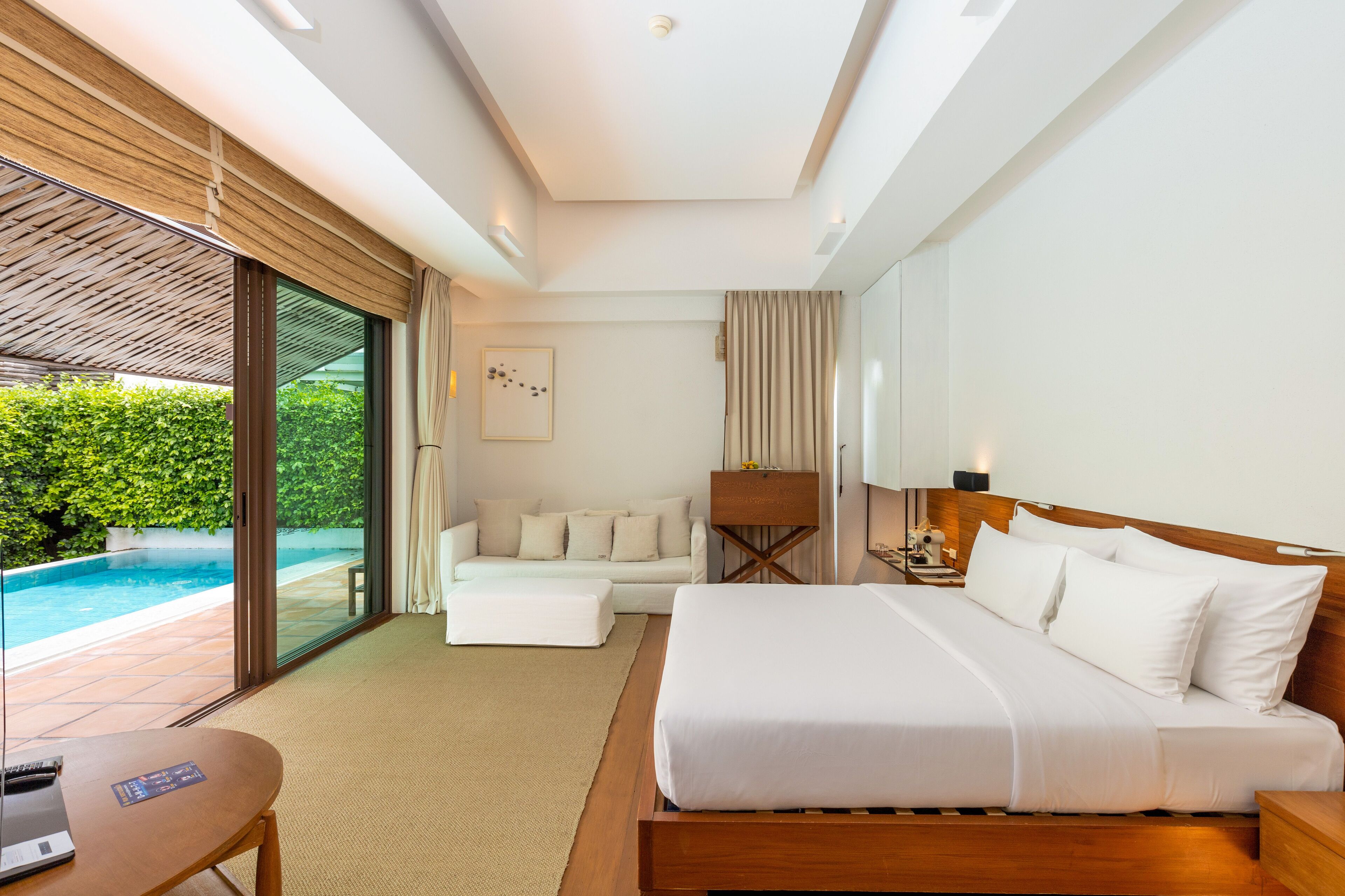 Una habitación de hotel moderna con una cama grande, un escritorio y vistas a una piscina.
