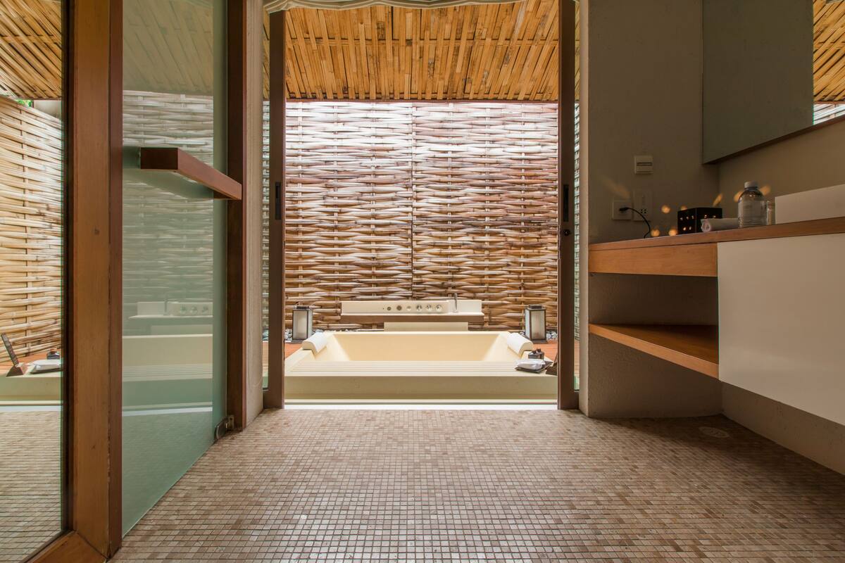 A modern bathroom with a large bathtub, a wooden ceiling, and a tiled floor.