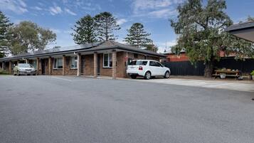 A single-story building with a brick facade, a carport, and a fenced yard.