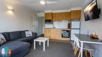 A modern kitchen with wooden cabinets, a microwave, a refrigerator, and a dining area with a table and chairs.