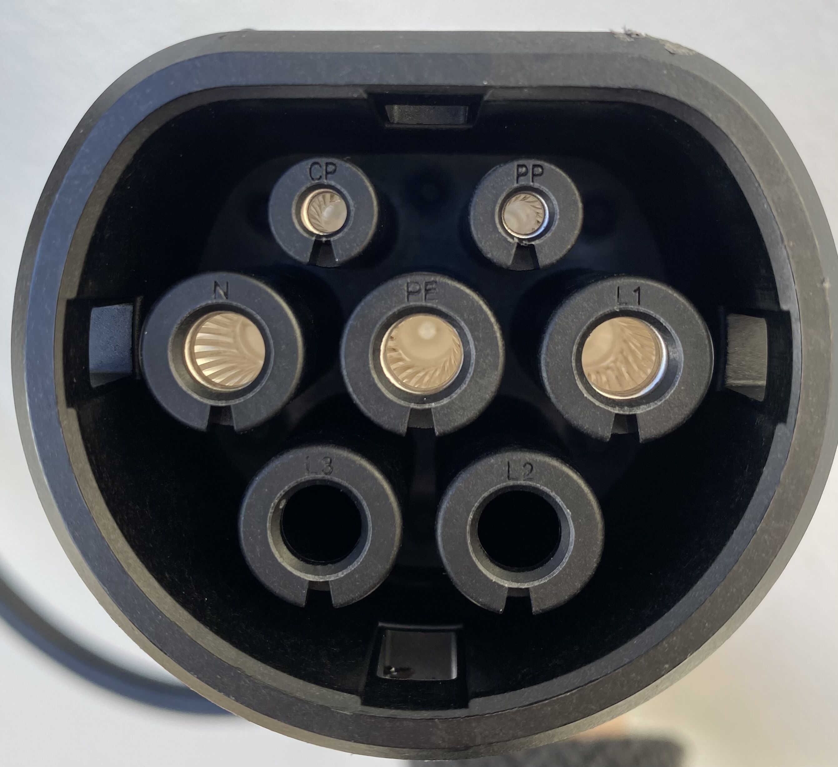 Primer plano de un enchufe eléctrico con varias tomas de corriente, incluyendo una de tres clavijas y una de dos.