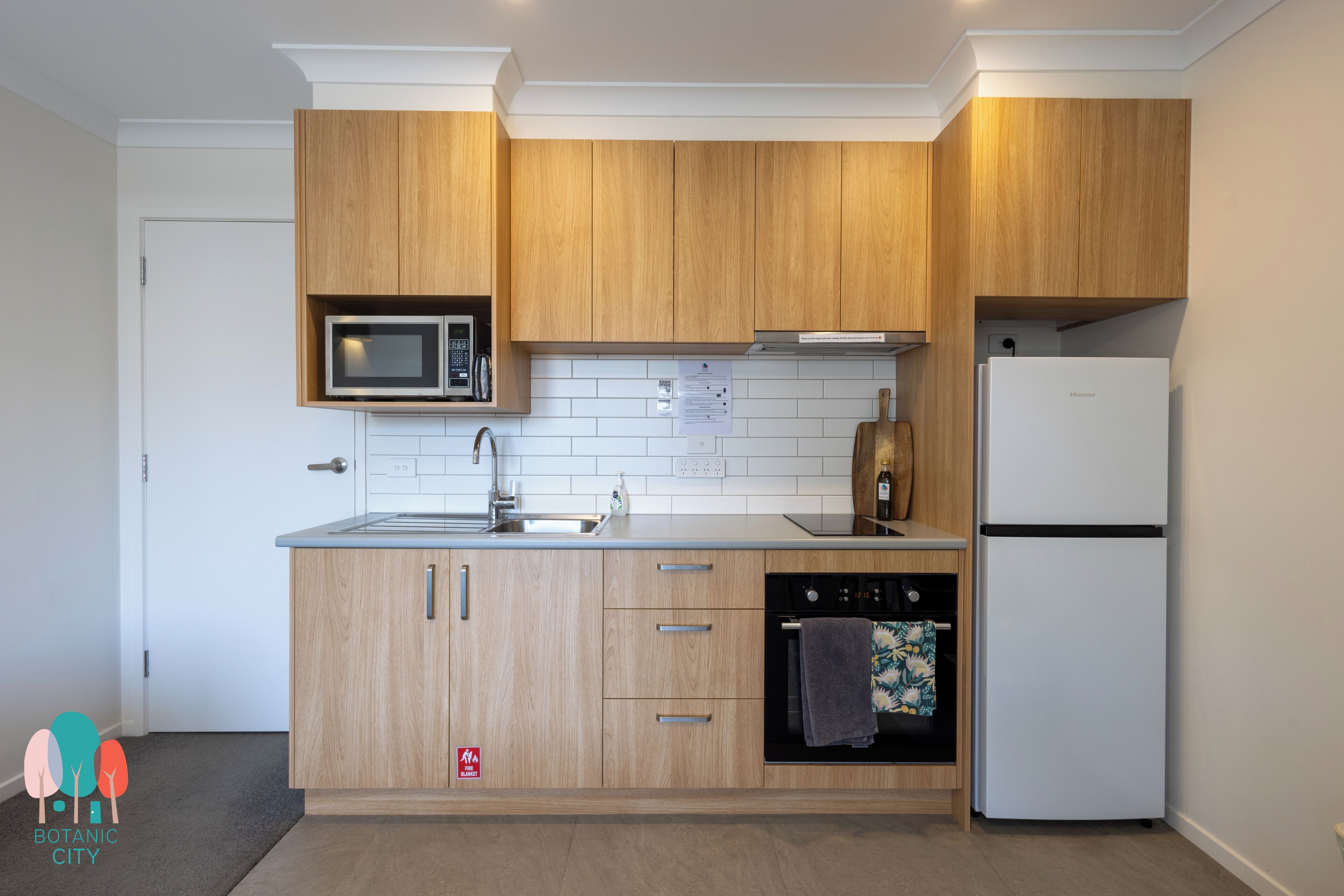 A modern kitchen with wooden cabinets, a microwave, a sink, a dishwasher, and a refrigerator.