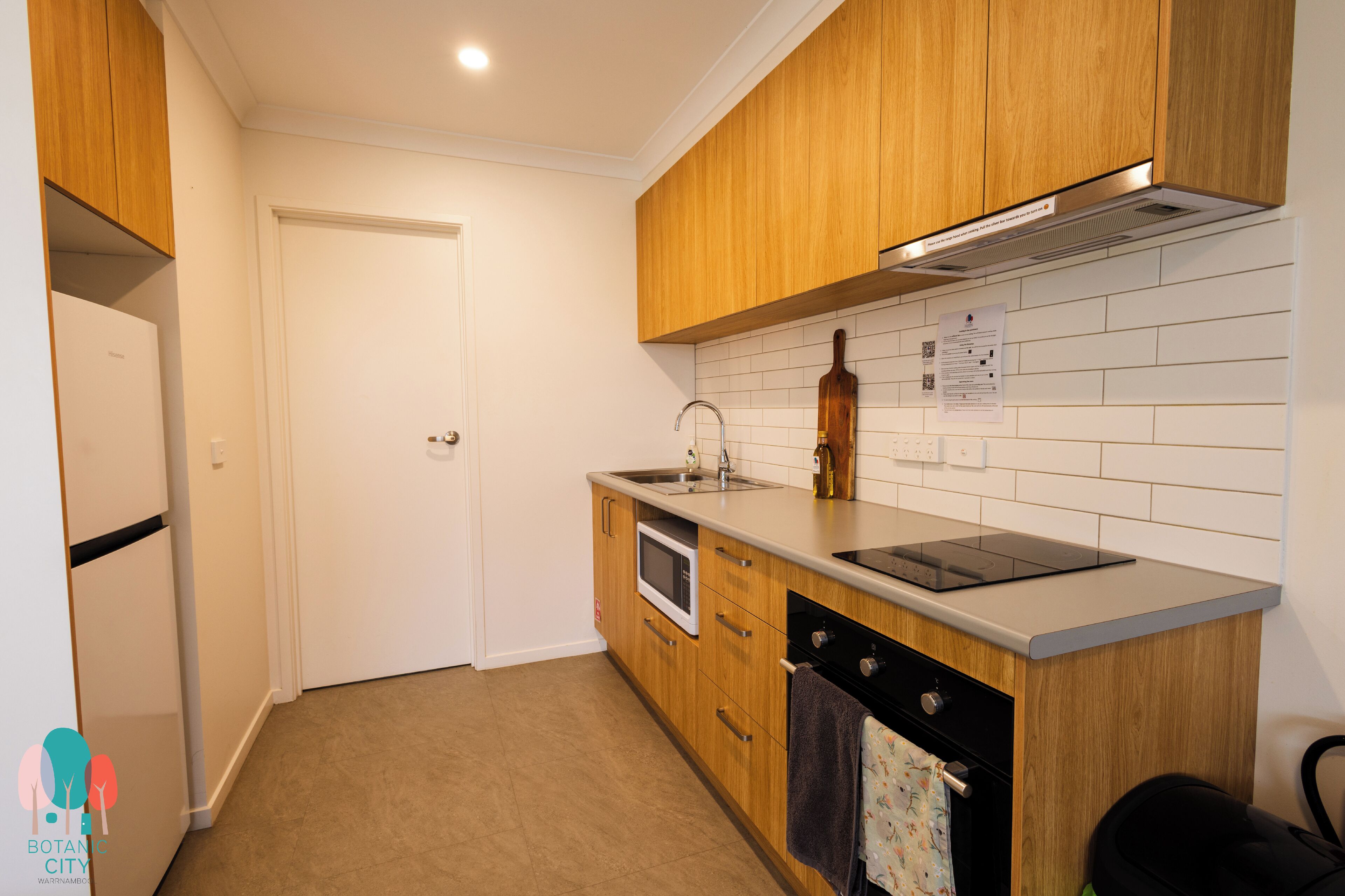 A compact kitchen with wooden cabinets, a built-in microwave, a sink, and a stove.