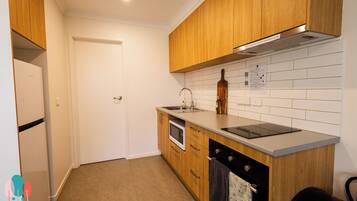 A compact kitchen with wooden cabinets, a built-in microwave, a sink, and a stove.