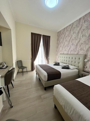 A hotel room with a large bed, a desk, and a chair. - Hotel Le Petit (Rome)