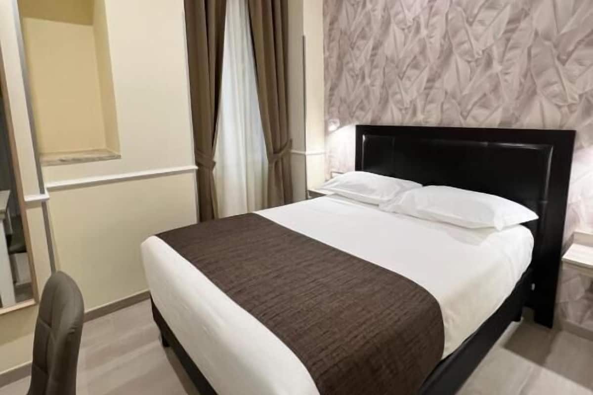 Una habitación de hotel con una cama, un escritorio y una silla.