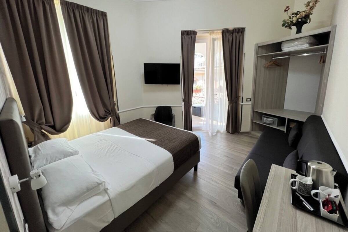 Una habitación de hotel con cama, escritorio con silla, televisor y armario.