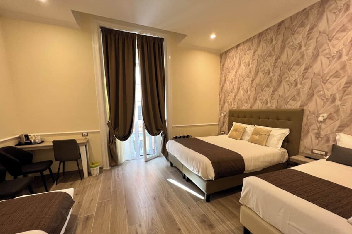 Habitación de hotel con dos camas, un escritorio y una silla.