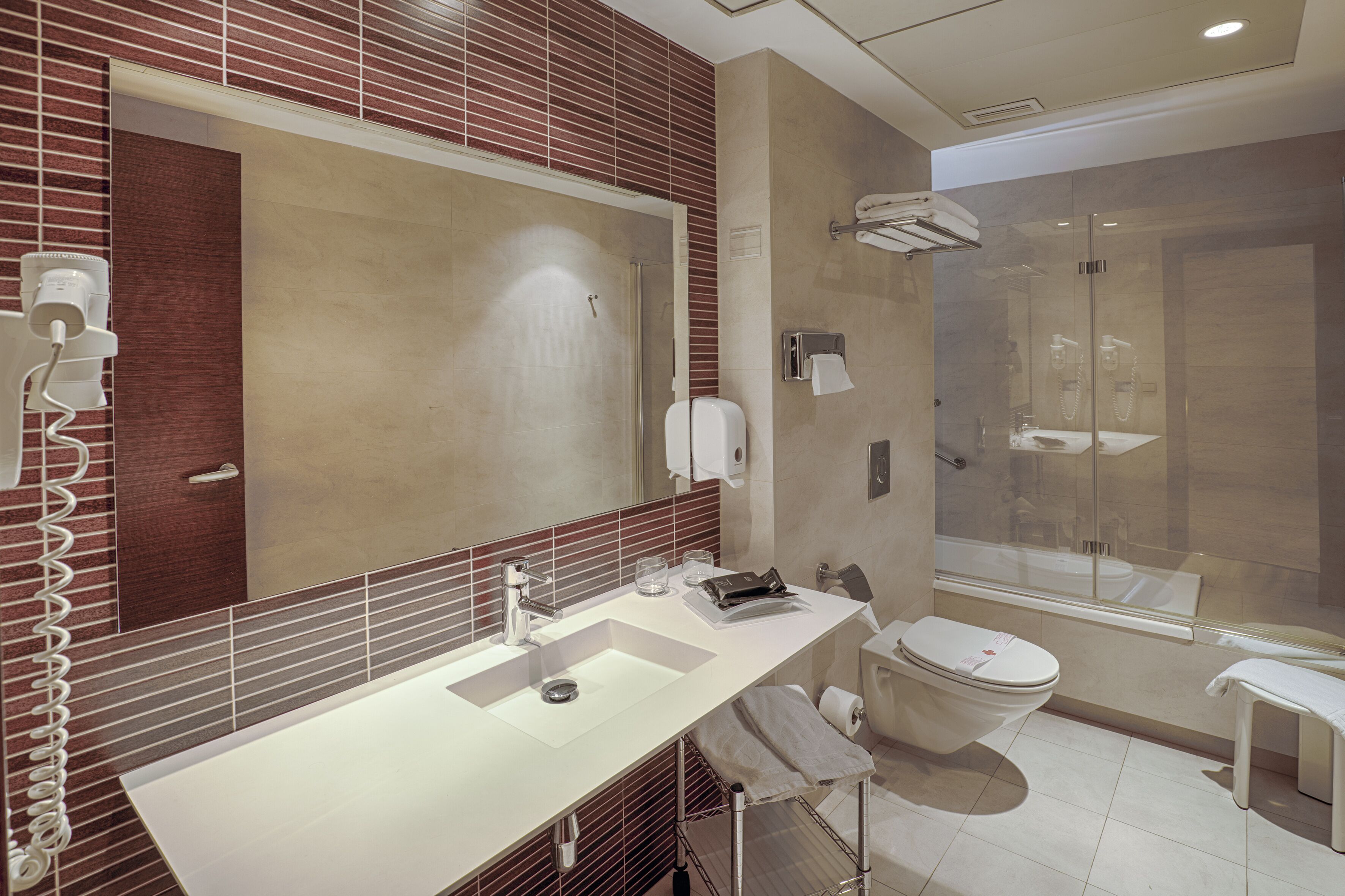 Ein modernes Badezimmer mit großem Spiegel, zwei Waschbecken, Toilette und einer Duschkabine.