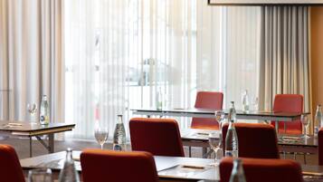 A conference room with glass tables, red chairs, and wine glasses.