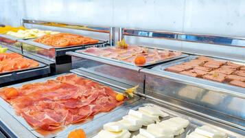Un bufé con diversos alimentos, incluyendo carnes, quesos y frutas.