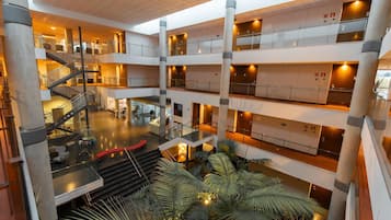 Un atrio de varios niveles con una escalera central, varios balcones y plantas de interior.